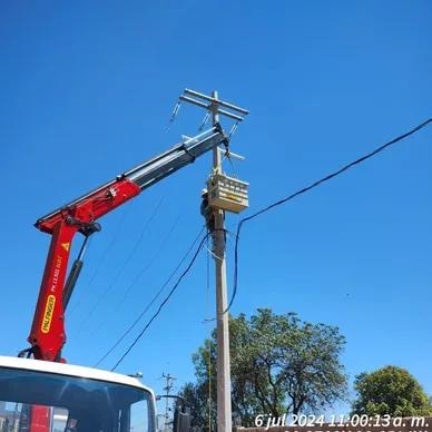 Grúa articulada instalando poste de media tensión